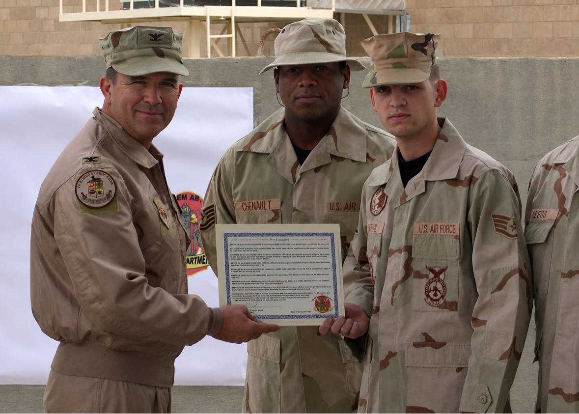 Jason McClaren in desert camouflage receiving a certificate while deployed