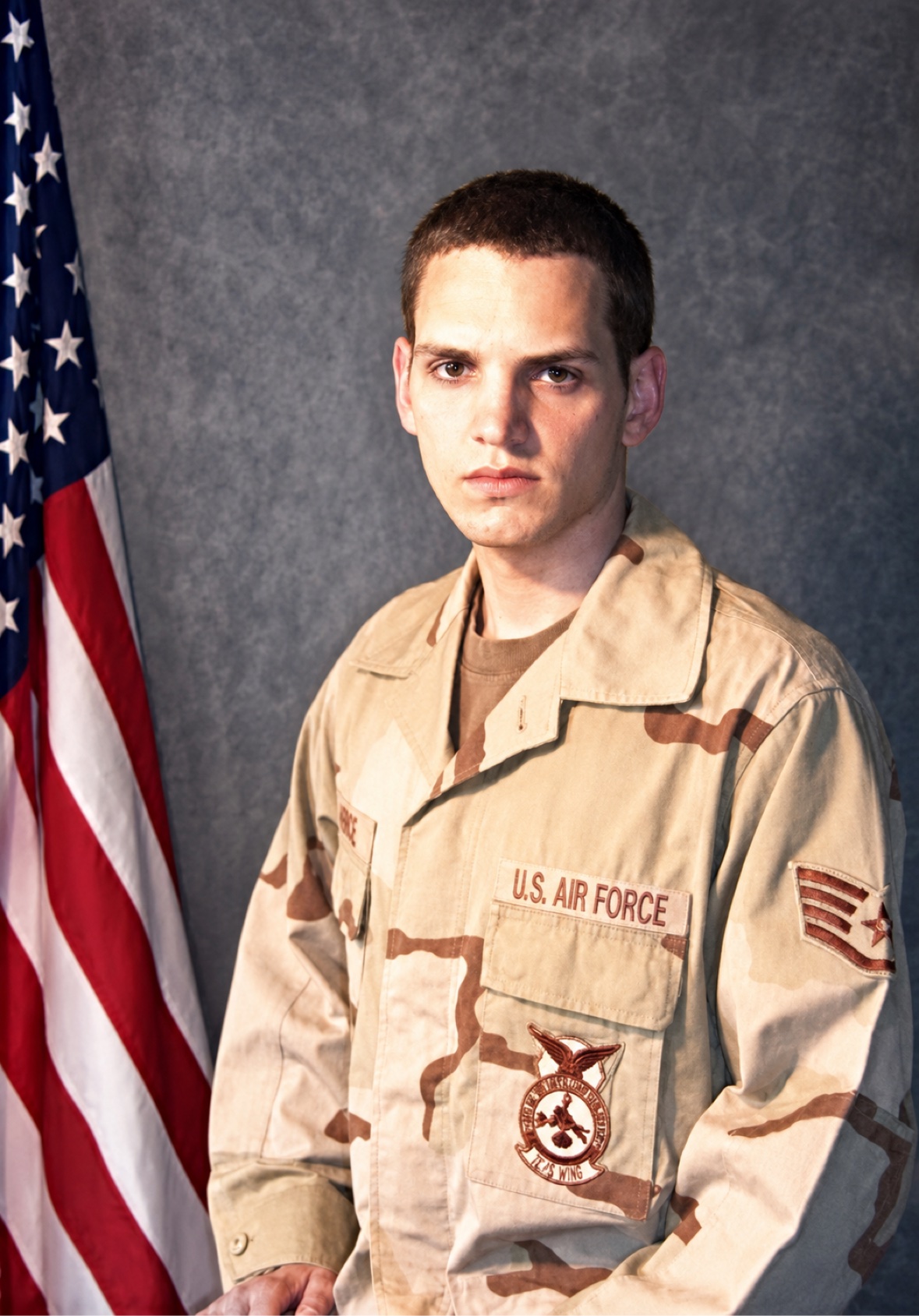 Portrait of Jason McClaren in U.S. Air Force desert camouflage beside the American flag