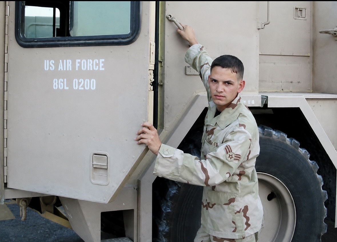Young Jason McClaren in desert camouflage climbing onto a U.S. Air Force fire truck